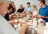 Bild: Tisch mit Essen und Mitarbeitern drum herum beim gemeinsamen essen 